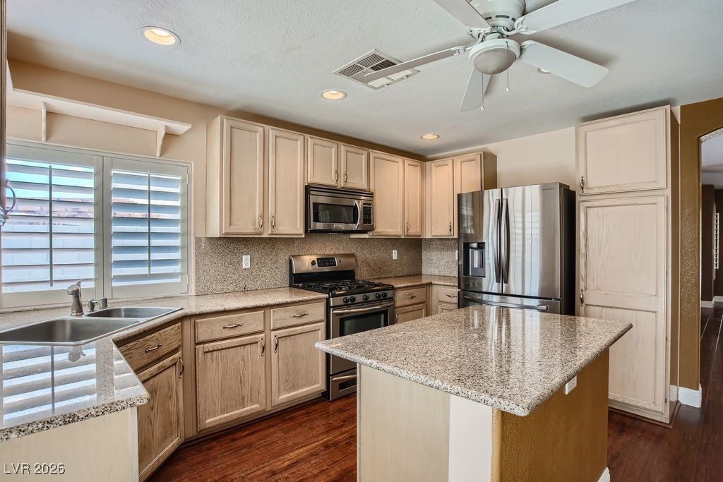 591 Fox Chase Street Henderson, NV 89015 - Photo 7 of 22 Kitchen with appliances with stainless steel finishes, light stone counters, dark wood finished floors, backsplash, and recessed lighting