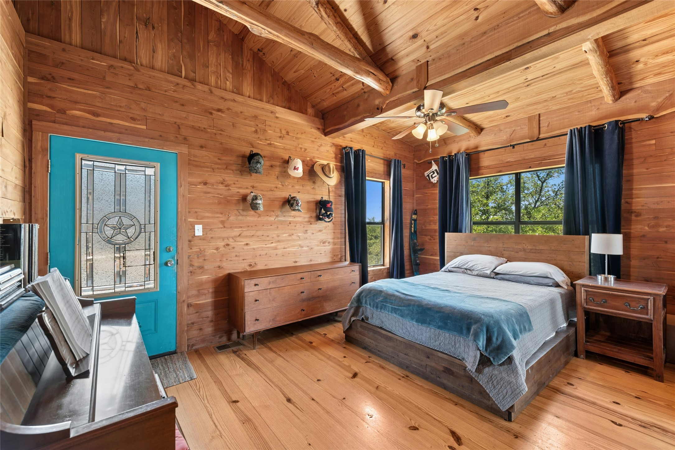 496 Middleton Road Spicewood, TX 78669 - Photo 22 of 40 Wood-paneled interior featuring vaulted ceilings with exposed wood beams, wood-finish flooring, a ceiling fan, and multiple windows