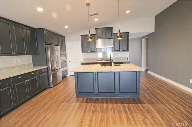 a kitchen with wooden floors stainless steel appliances and cabinets