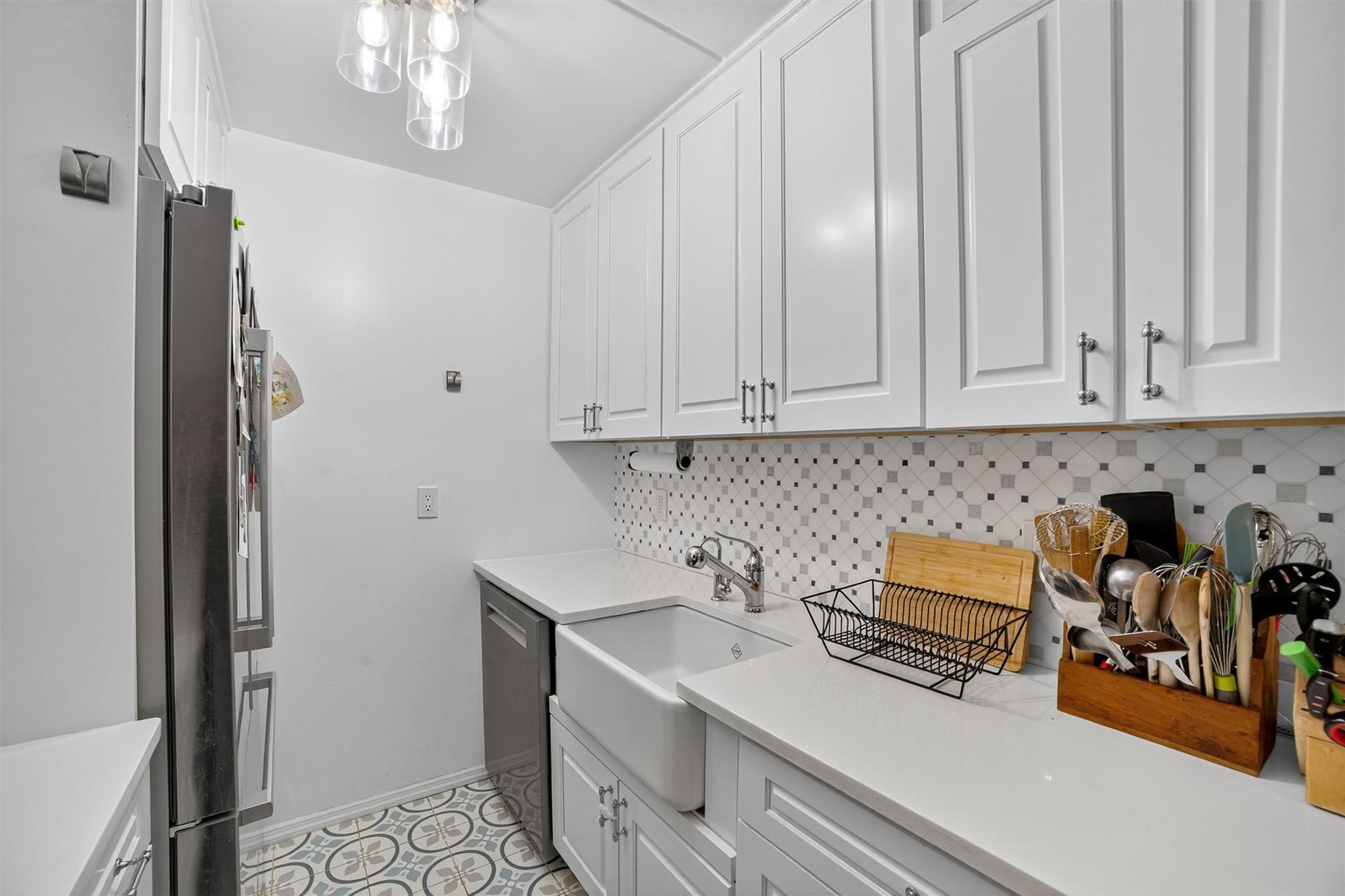 108 Sagamore Road, Unit 5F Tuckahoe, NY 10707 - Photo 22 of 33 Kitchen with stainless steel appliances, white cabinetry, light countertops, and decorative backsplash