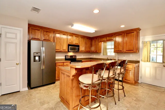 a kitchen with stainless steel appliances granite countertop a refrigerator a stove top oven and a dining table with wooden floor