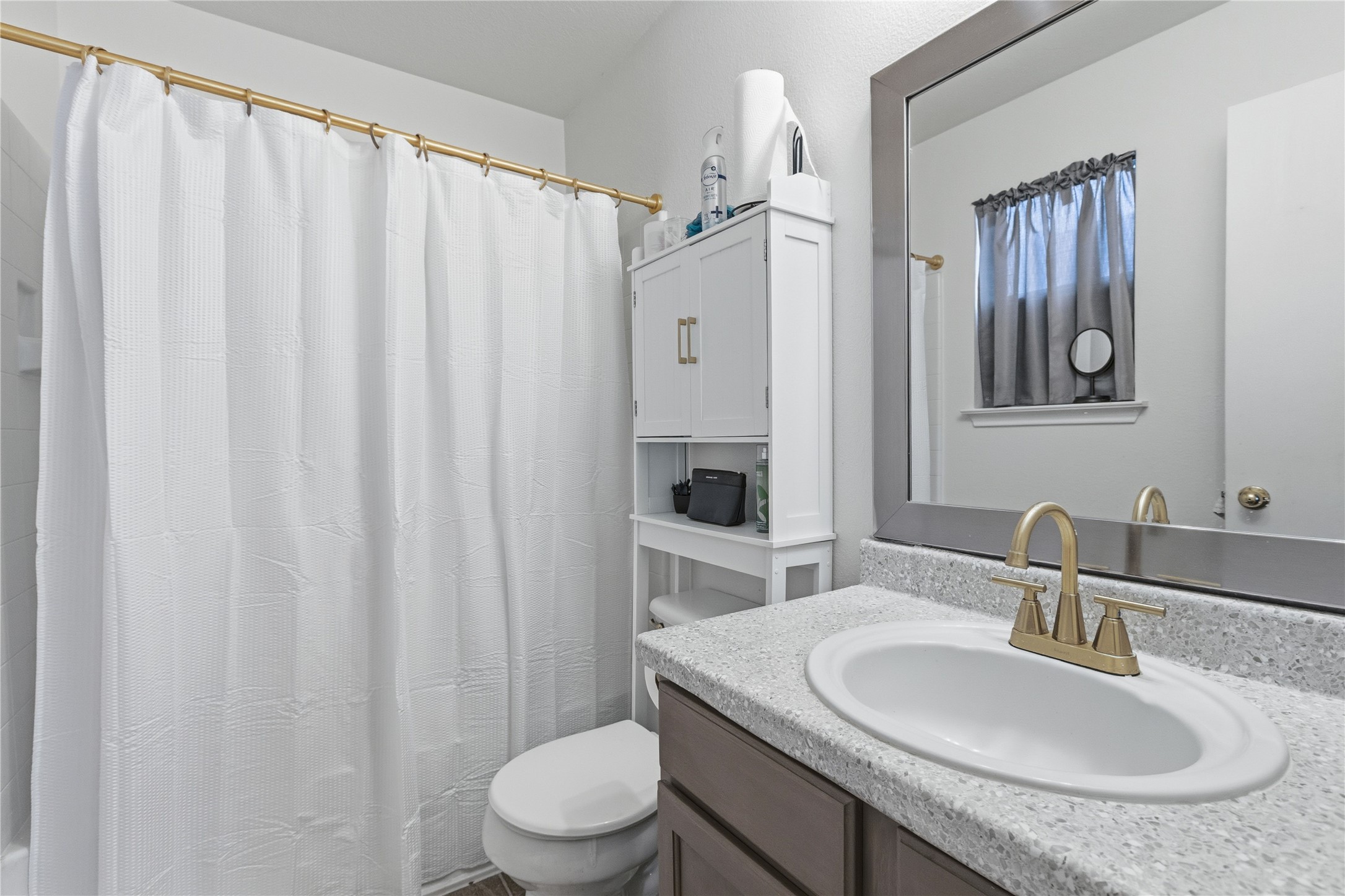 16112 Hamilton Point Circle Manor, TX 78653 - Photo 25 of 27 Full bathroom featuring a white vanity with a speckled countertop, an oval undermount sink, and a gold-finish faucet