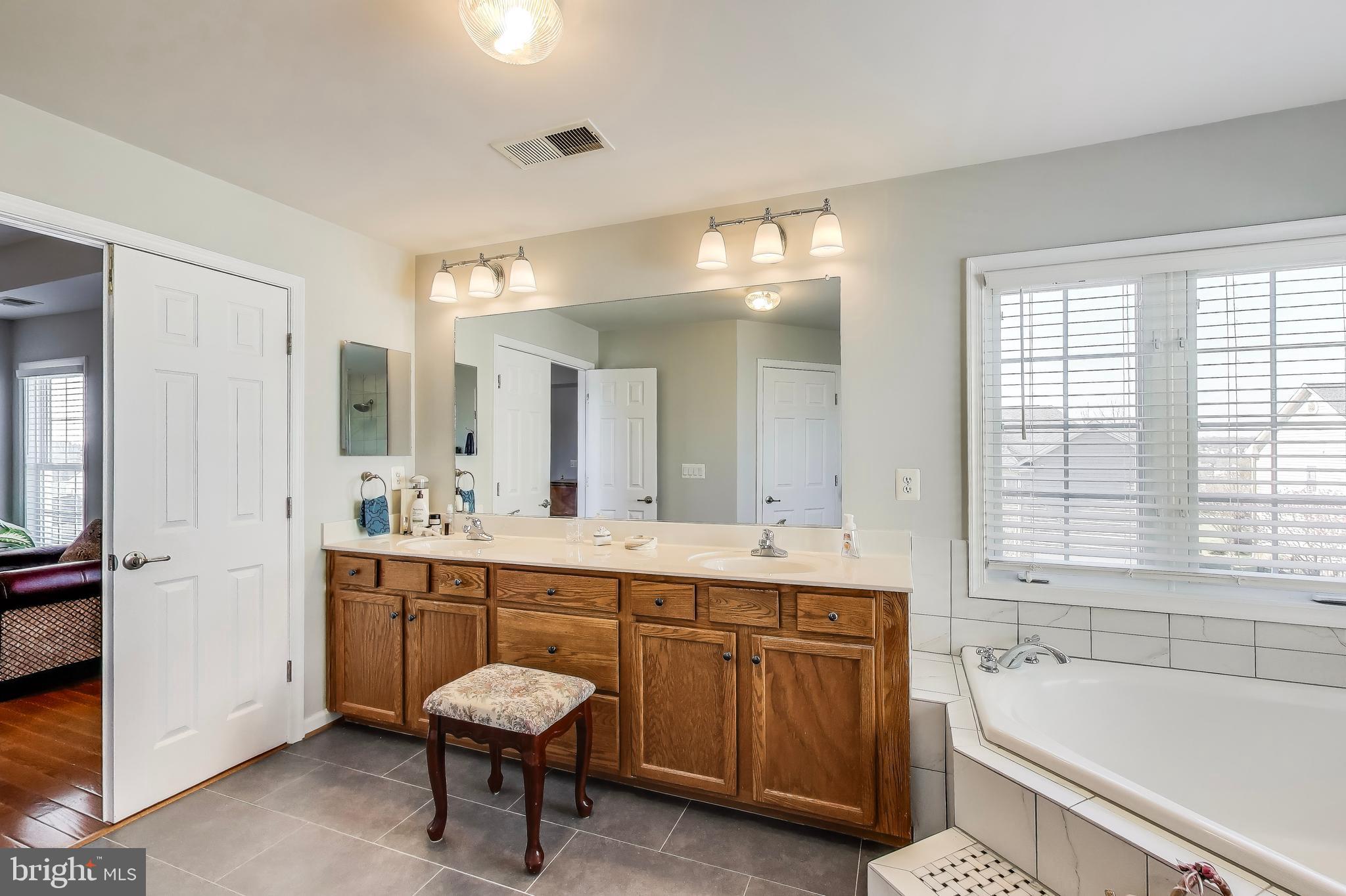 16180 Radburn Street Woodbridge, VA 22191 - Photo 26 of 54 a spacious bathroom with a tub a sink and a large mirror
