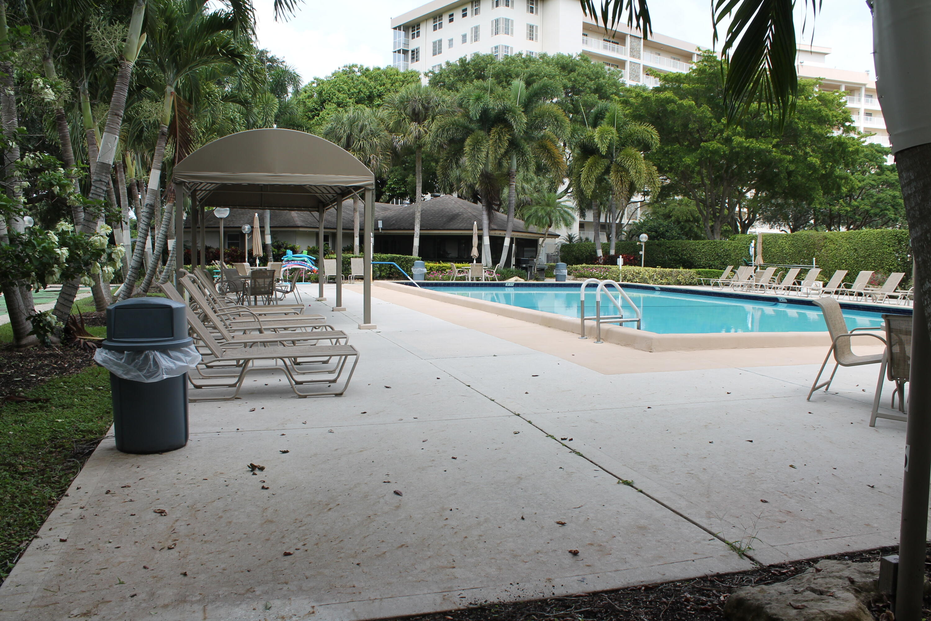 3520 Oaks Way, Unit 607 Pompano Beach, FL 33069 - Photo 36 of 46 a view of patio with table and chairs under an umbrella with large trees