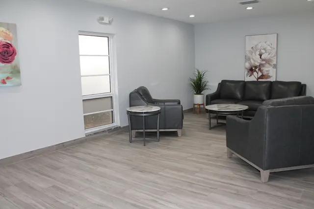 a view of a patio with chairs and a table and chairs under an umbrella with large trees