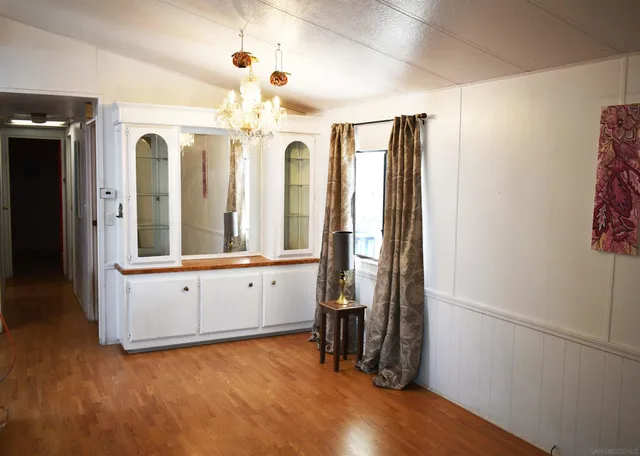 a view of a hallway with chandelier and wooden floors