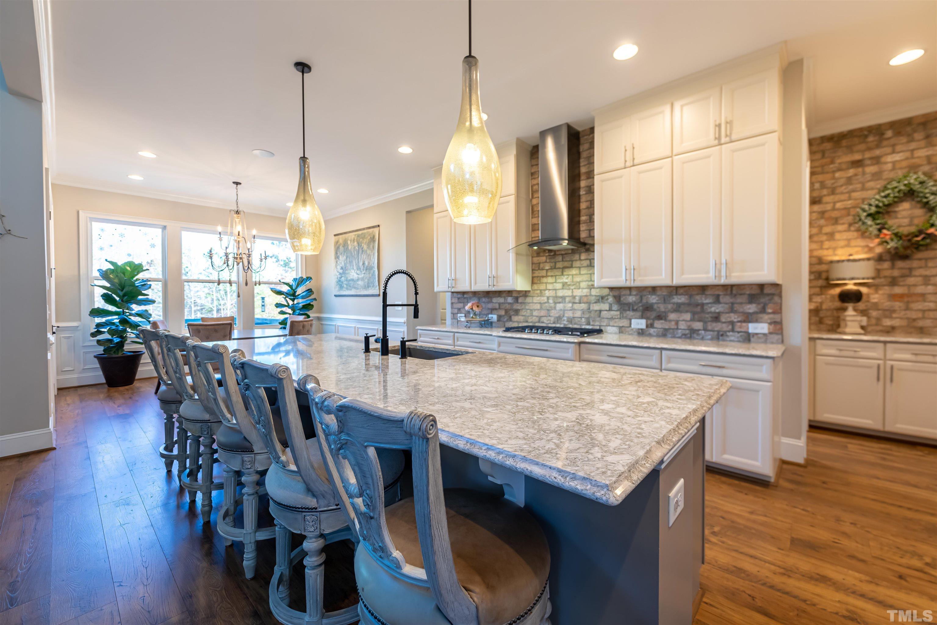 456 Adkins Ridge Road Rolesville, NC 27571 - Photo 6 of 38 a kitchen with granite countertop a table chairs sink and wooden floor