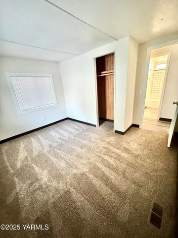 a view of an empty room with closet and a window