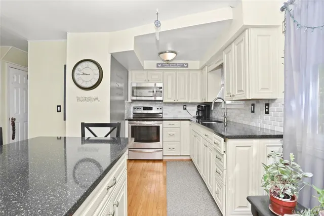 a kitchen with granite countertop a white cabinets sink and stainless steel appliances