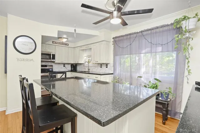 a kitchen with stainless steel appliances granite countertop a table chairs in it and wooden floors