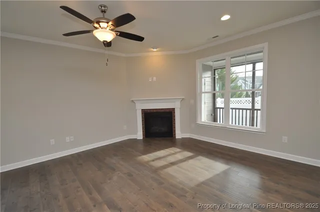an empty room with chandelier fan and windows