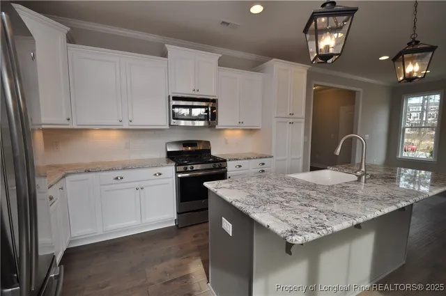 a kitchen with granite countertop stainless steel appliances sink stove and cabinets