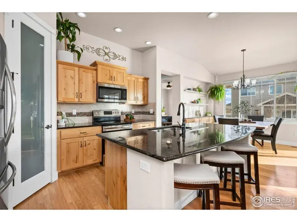 a kitchen with stainless steel appliances granite countertop a refrigerator a stove top oven and a view of living room