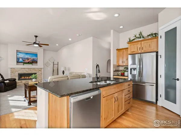 a kitchen with stainless steel appliances granite countertop a sink and a living room view