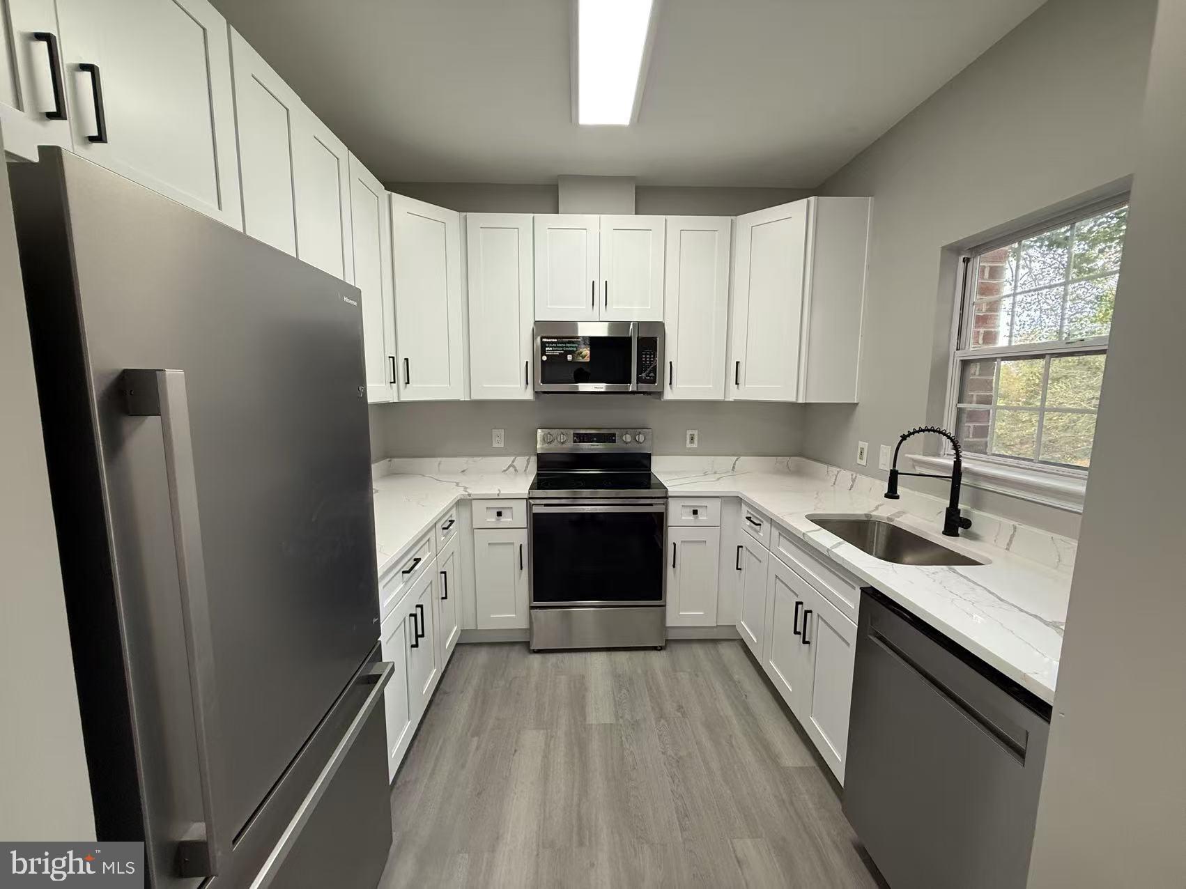 4400 Silverbrook Lane, Unit F003 Owings Mills, MD 21117 - Photo 2 of 17 a kitchen with a refrigerator a sink and white cabinets