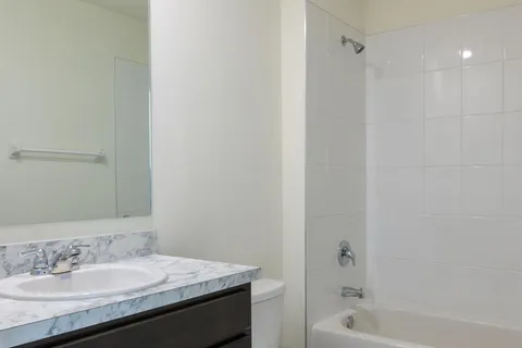 a bathroom with a granite countertop sink a mirror and a bathtub