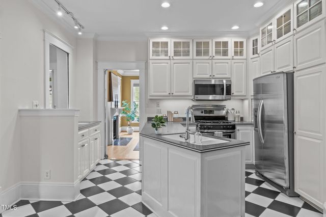 a living room with a black white checkered floor with a dining table and chair