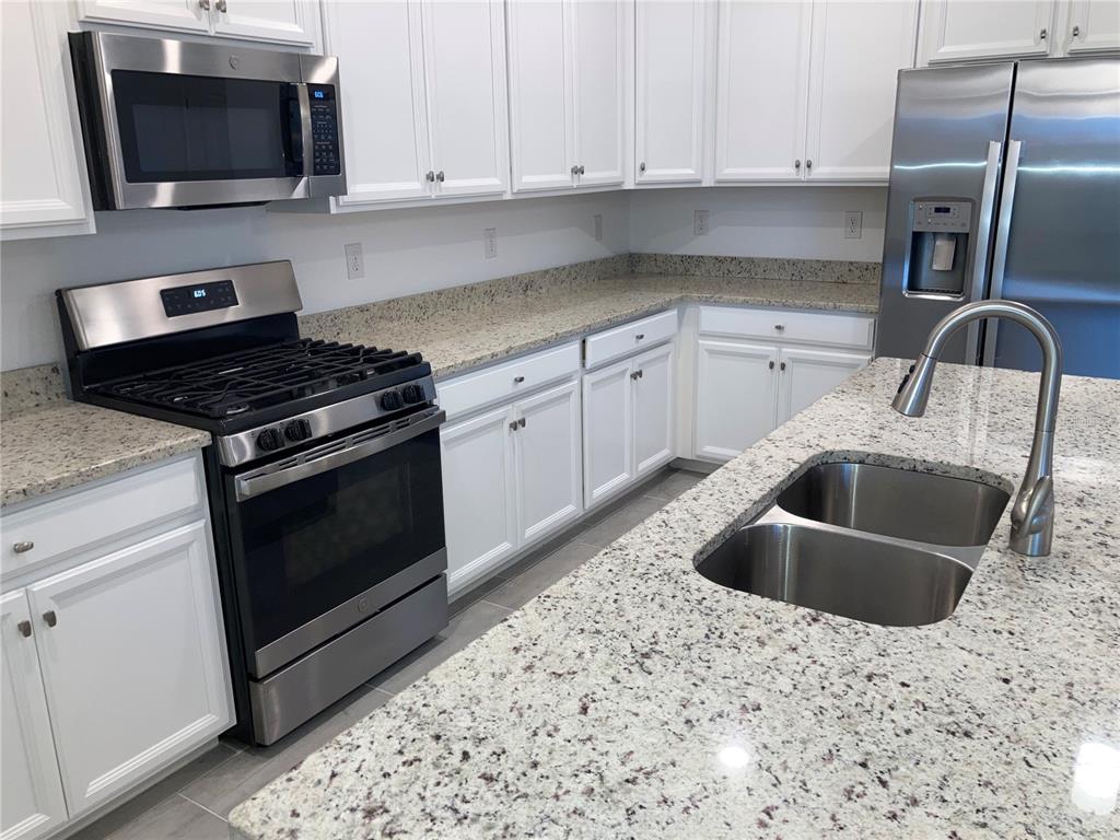 6511 Clairborne Lane Bradenton, FL 34211 - Photo 4 of 12 a kitchen with stainless steel appliances granite countertop a sink and a stove top oven