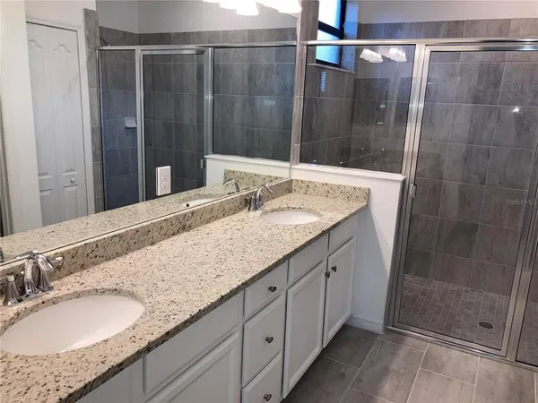 a bathroom with a granite countertop sink a mirror and shower
