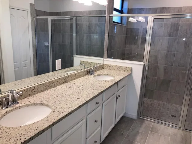 a bathroom with a granite countertop sink a mirror and shower