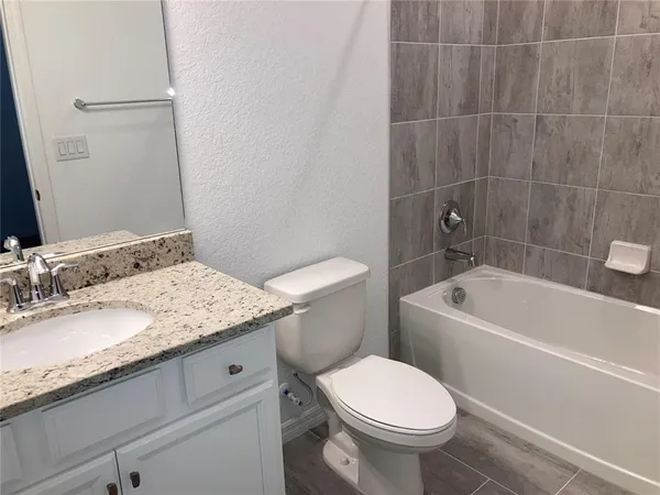 a bathroom with a granite countertop toilet a sink and bathtub
