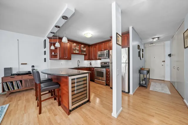a kitchen with stainless steel appliances granite countertop a table chairs and a refrigerator