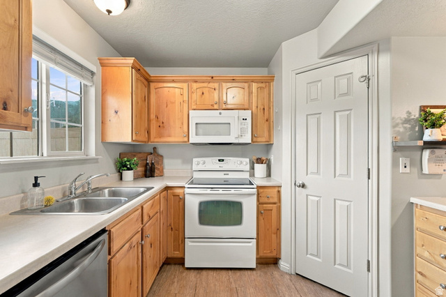 1041 South 1850th Street West Springville, UT 84663 - Photo 12 of 35 Kitchen featuring wood-finish cabinetry, white appliances, dual stainless steel sink, and wood-look flooring
