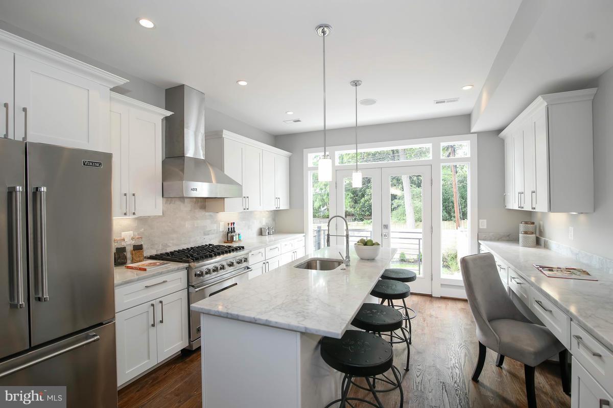 a kitchen with stainless steel appliances kitchen island a table chairs refrigerator and microwave