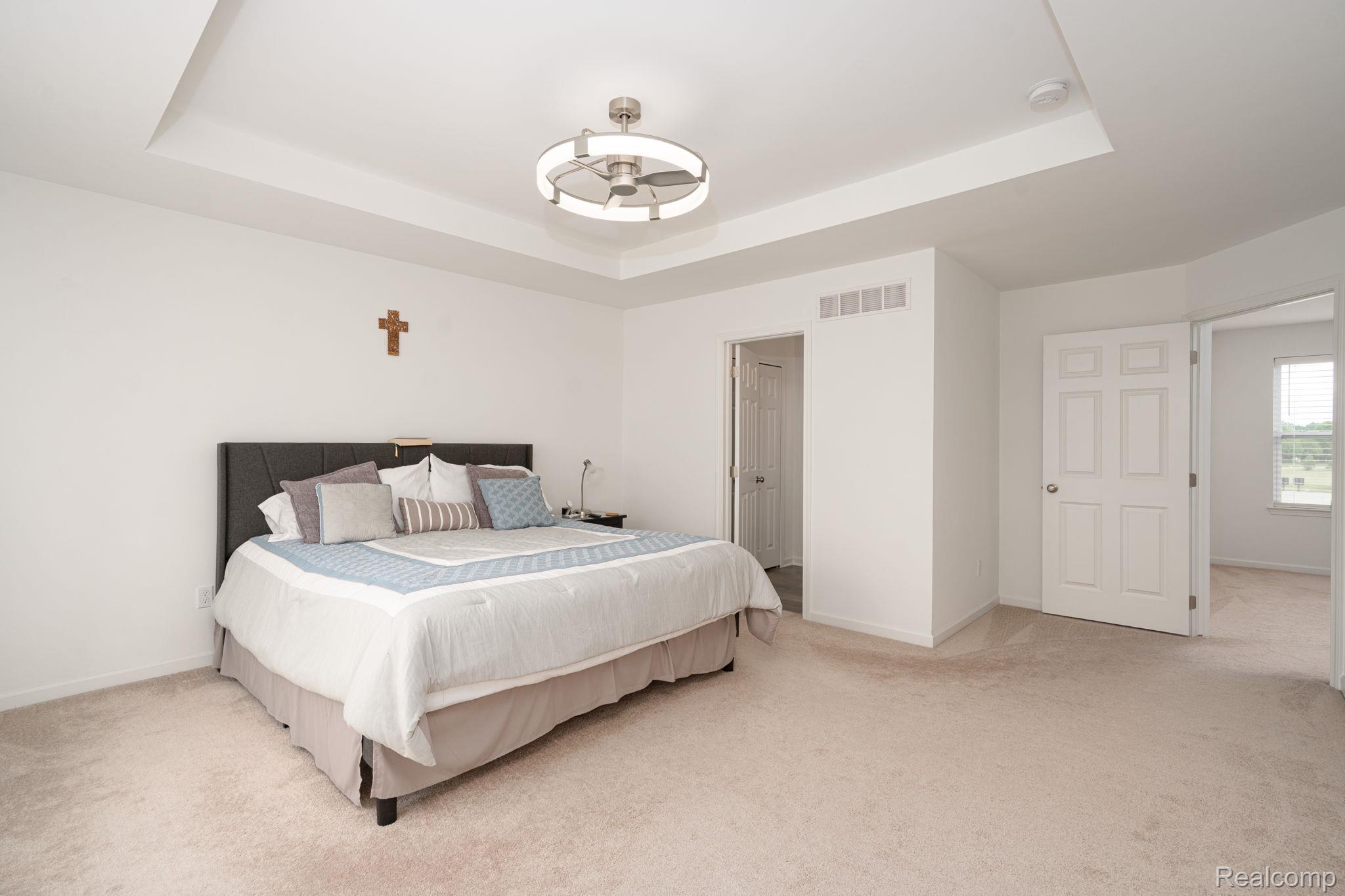 48904 Carnegie Way Macomb, MI 48042 - Photo 21 of 34 Spacious room featuring a tray ceiling with a contemporary ceiling fan, light beige carpet, and white walls