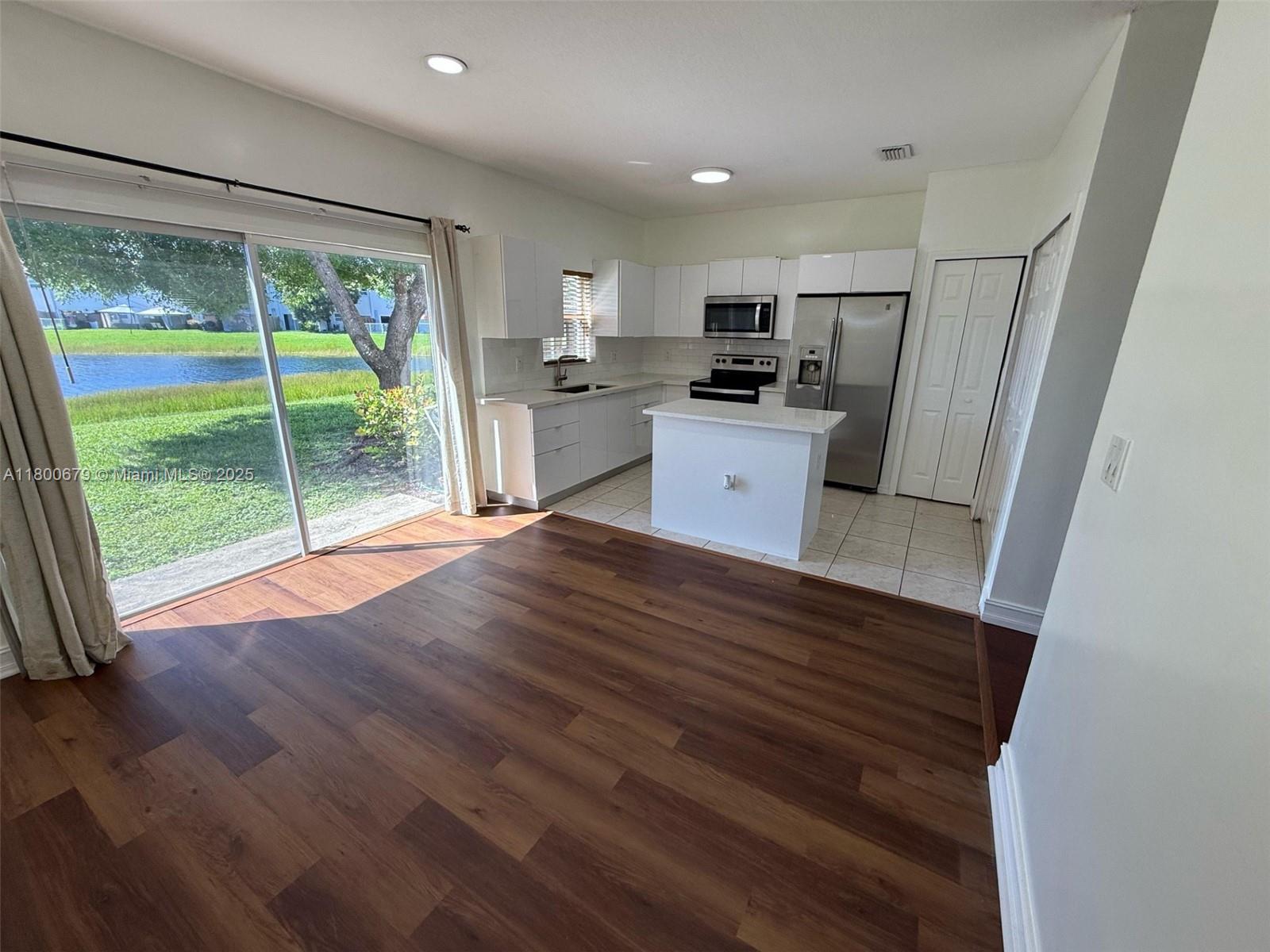 a kitchen with stainless steel appliances wooden floors and white cabinets