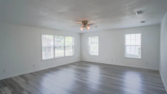a view of a room with wooden floor and a ceiling fan