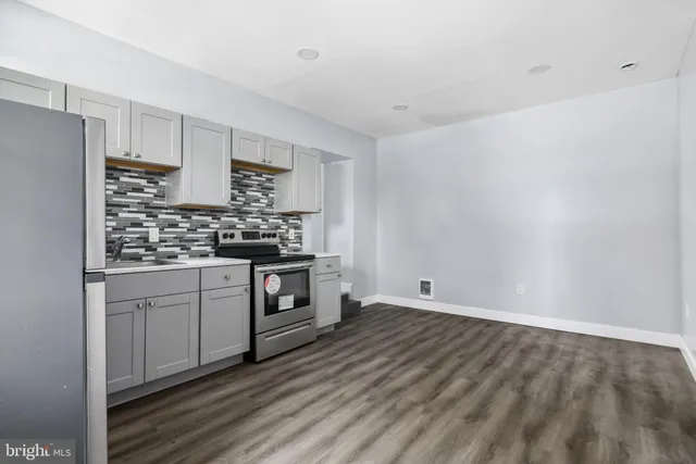 a kitchen with stainless steel appliances a stove a sink and white cabinets