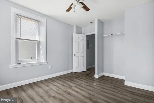 an empty room with wooden floor cabinet and windows
