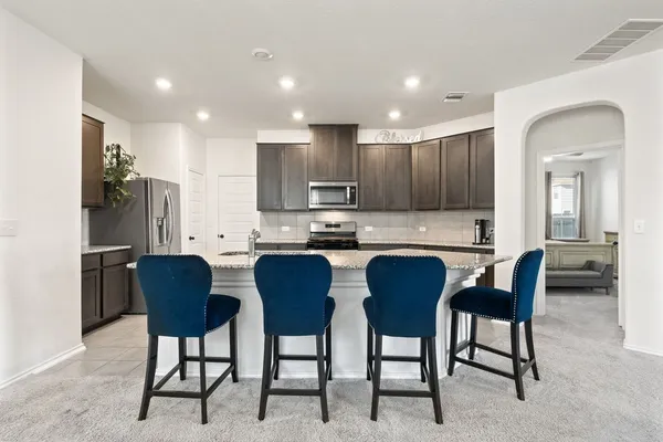 a view of kitchen with refrigerator stove dining table and chairs