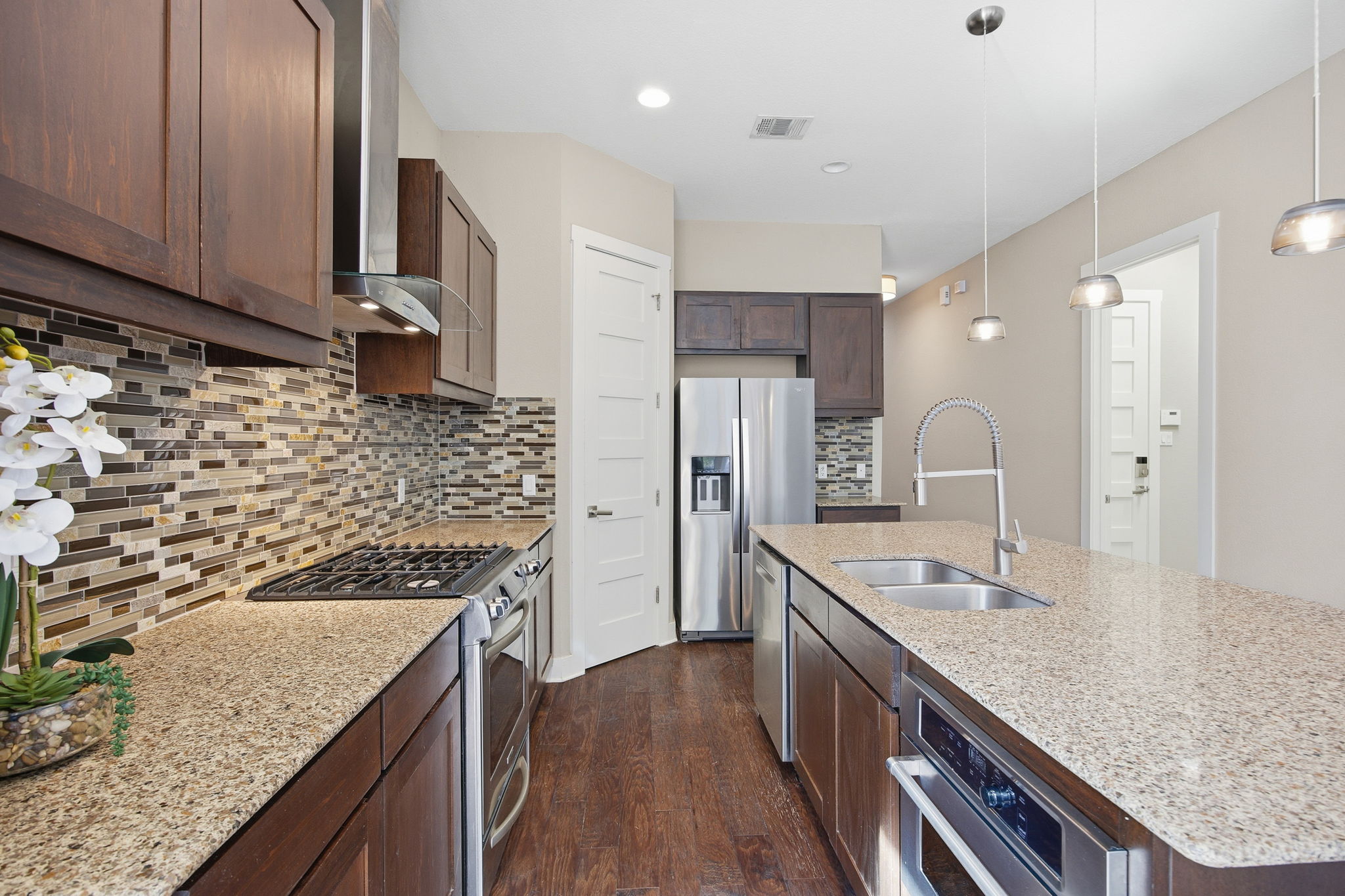 3521 Marcae Court Austin, TX 78704 - Photo 11 of 37 Kitchen with dark wood finish cabinets, stainless steel appliances, tasteful backsplash, and dark wood-type flooring