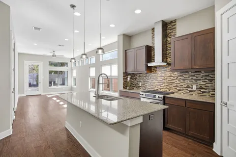 a kitchen with stainless steel appliances granite countertop a sink a stove and a wooden floors