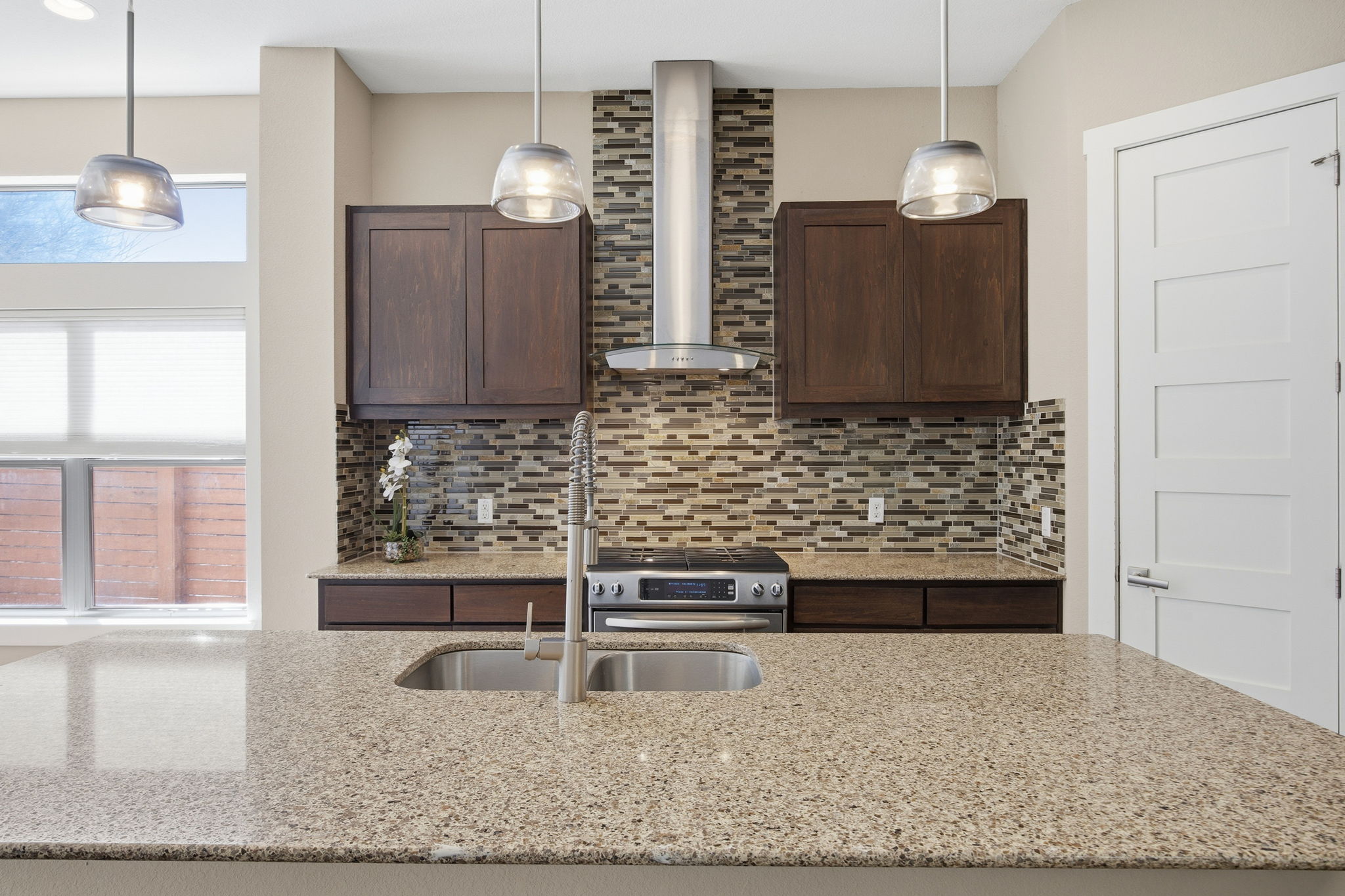 3521 Marcae Court Austin, TX 78704 - Photo 4 of 37 Kitchen featuring dark wood finish cabinetry, hanging light fixtures, light stone counters, stainless steel range oven, and decorative backsplash