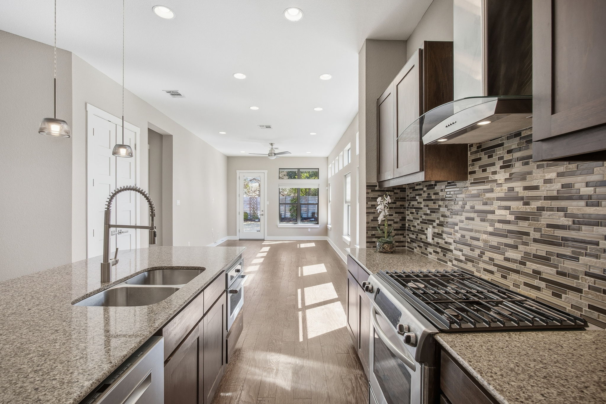 3521 Marcae Court Austin, TX 78704 - Photo 8 of 37 Kitchen with stainless steel appliances, light wood-style floors, light stone counters, decorative backsplash, and decorative light fixtures