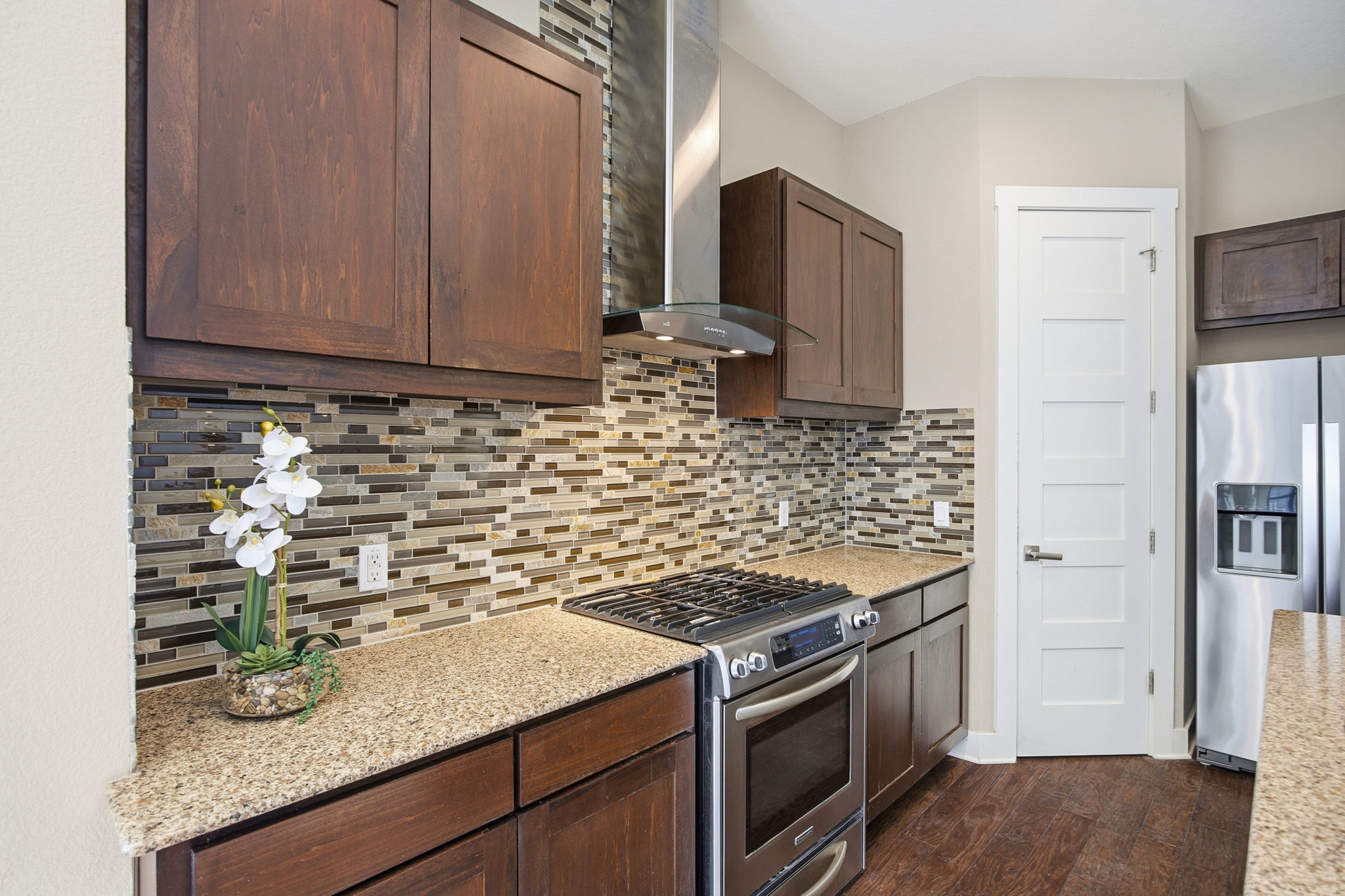 3521 Marcae Court Austin, TX 78704 - Photo 9 of 37 Kitchen featuring stainless steel appliances, decorative backsplash, light stone counters, dark wood-style flooring, and dark wood finish cabinetry