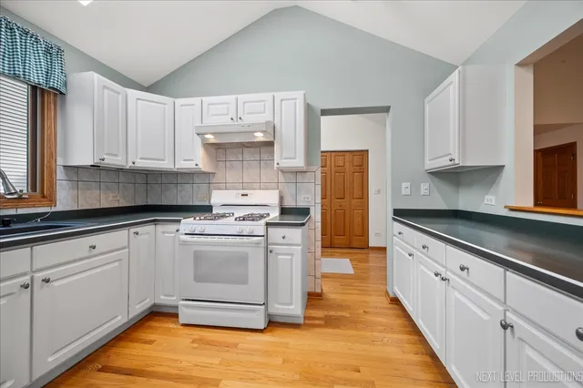 a kitchen with stainless steel appliances granite countertop a stove a sink and white cabinets