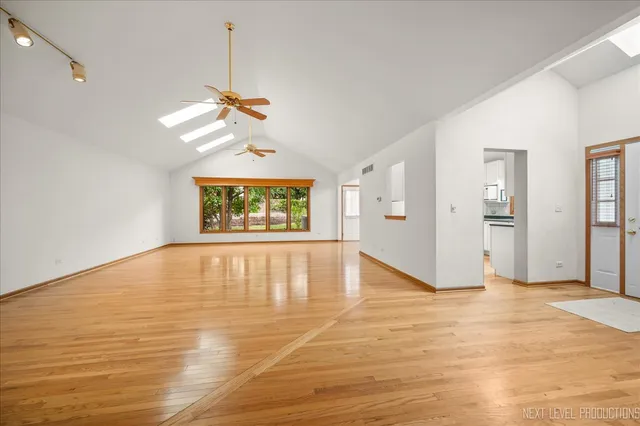 a view of an empty room with window and wooden floor