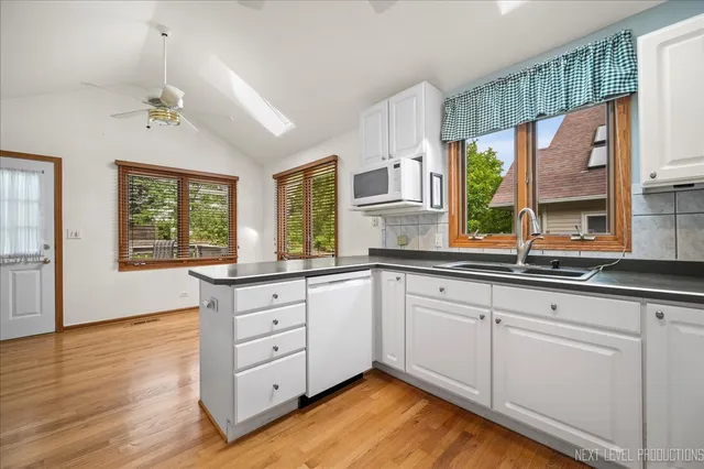 a kitchen with granite countertop a stove a sink and white cabinets with wooden floor