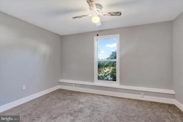 an empty room with windows and fan view