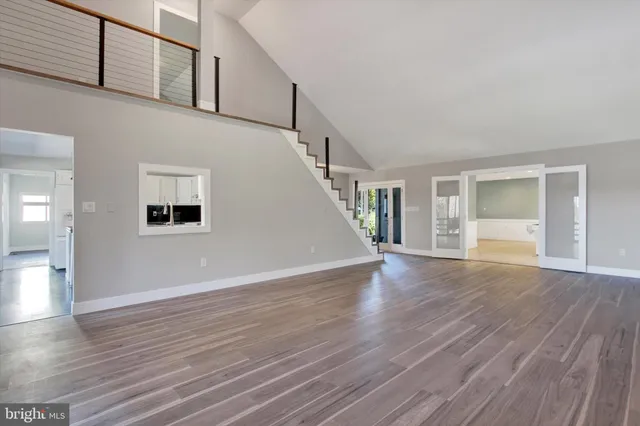 a view of an empty room with wooden floor and stairs