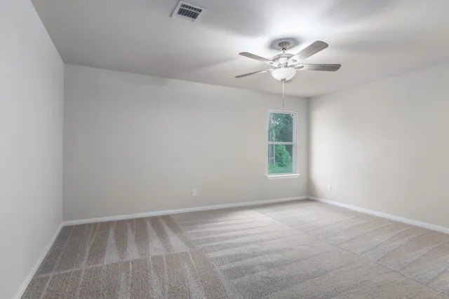 an empty room with a chandelier fan and windows