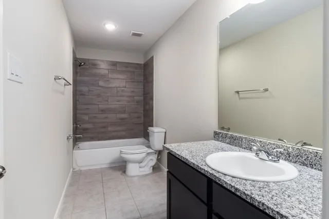 a bathroom with a granite countertop bathtub sink vanity mirror and toilet