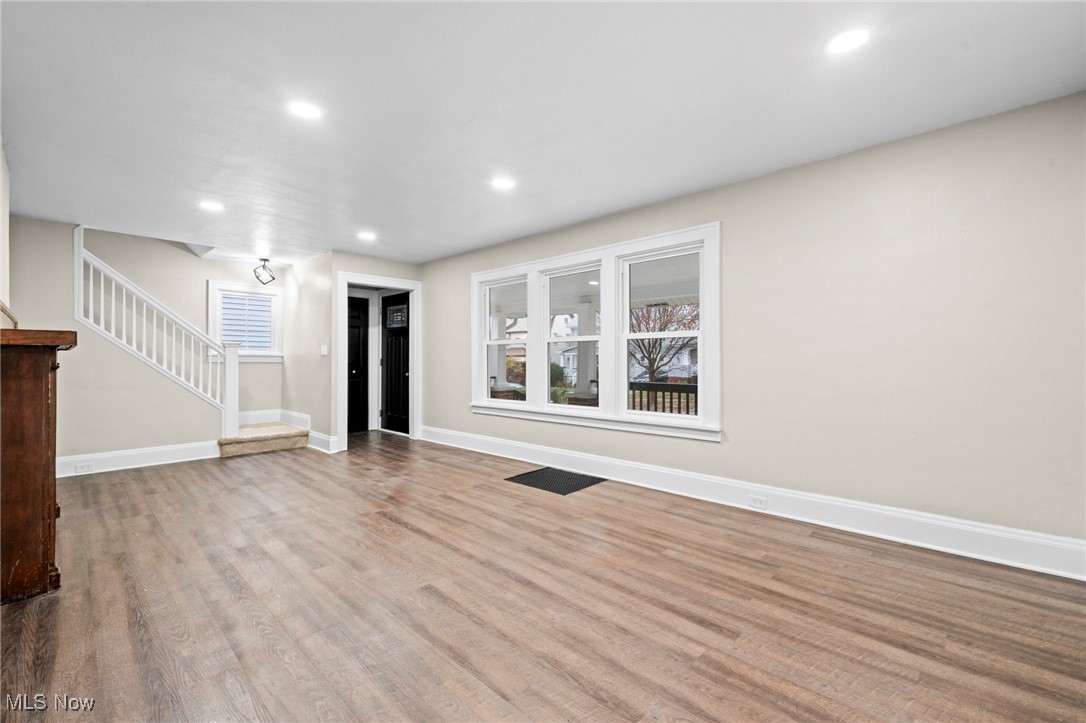 Unfurnished living room with recessed lighting, wood finished floors, and stairs