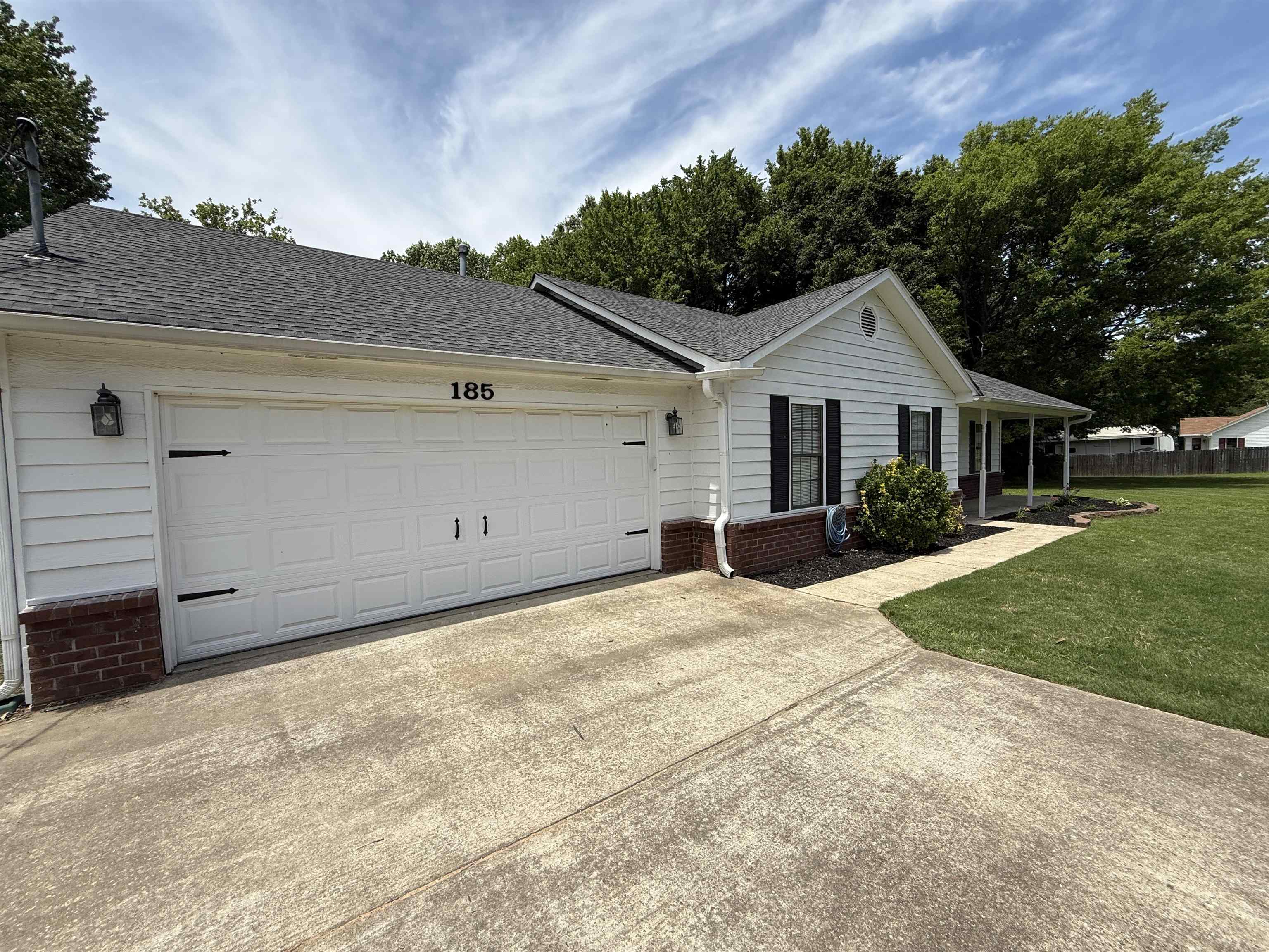 185 Mignon Road Atoka, TN 38004 - Photo 6 of 34 Exterior featuring white siding, a two-car garage with decorative hardware and exterior lighting, and a dark shingle roof