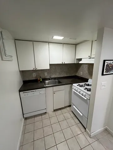 a kitchen with granite countertop a stove top oven and cabinets