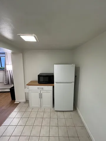 a kitchen with a refrigerator and white cabinets